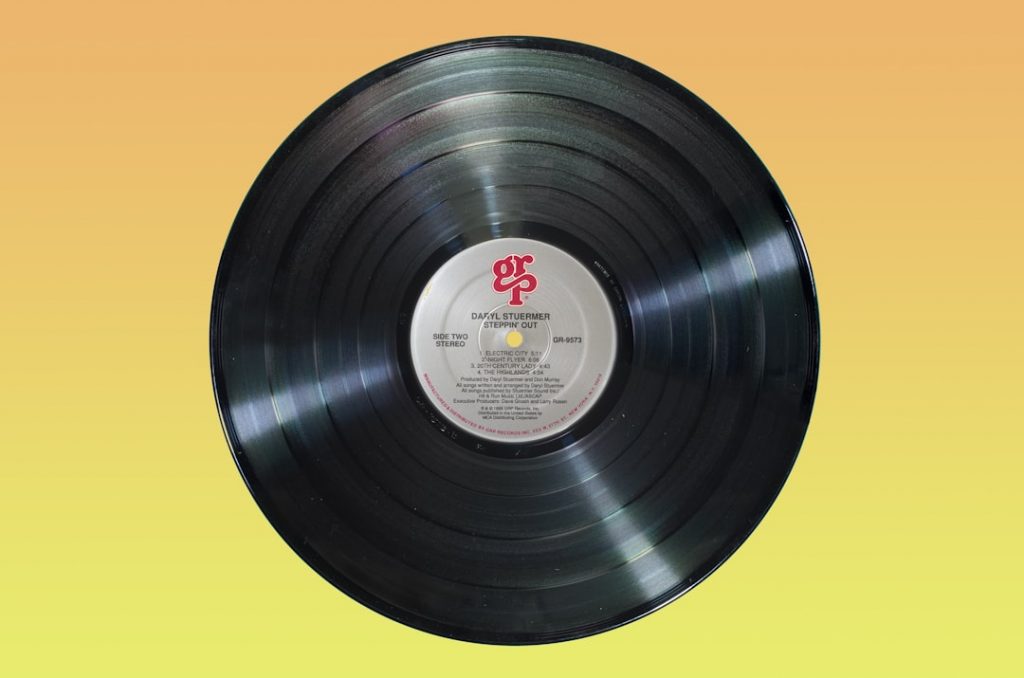 Disque vinyle sur fond jaune, illustration d’une certification musicale. Photo : Immo Wegmann / Unsplash.