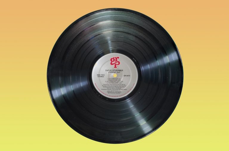 Disque vinyle sur fond jaune, illustration d’une certification musicale. Photo : Immo Wegmann / Unsplash.